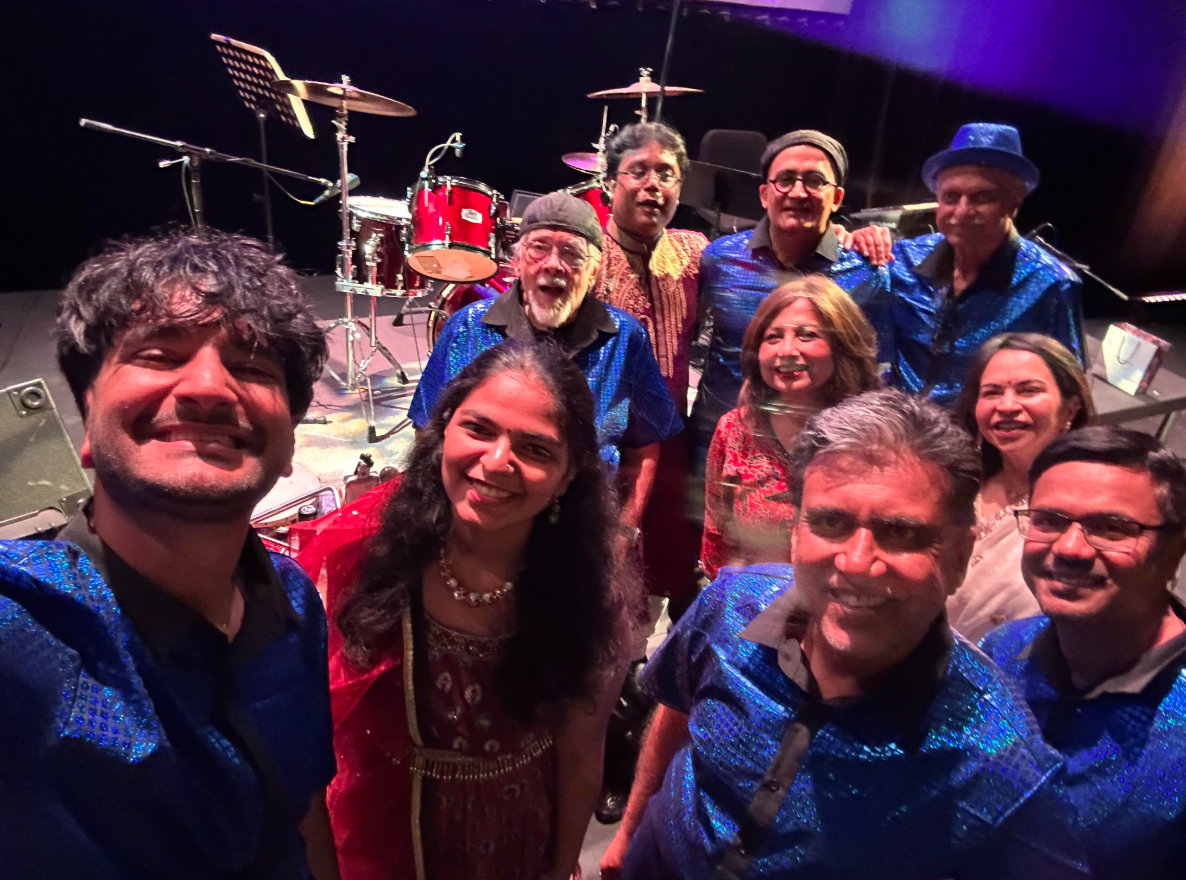 The Chili Beatz band members smiling together on stage in front of the drum kit after a show