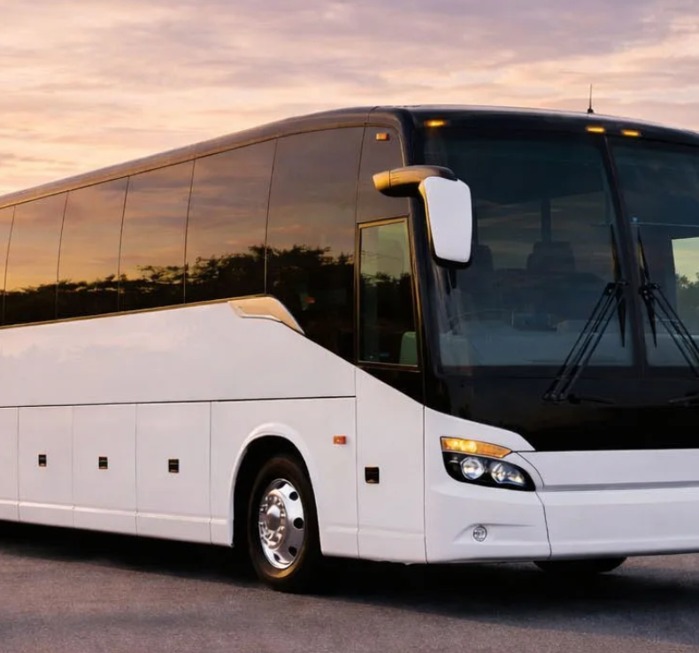 White luxury coach bus parked at sunset